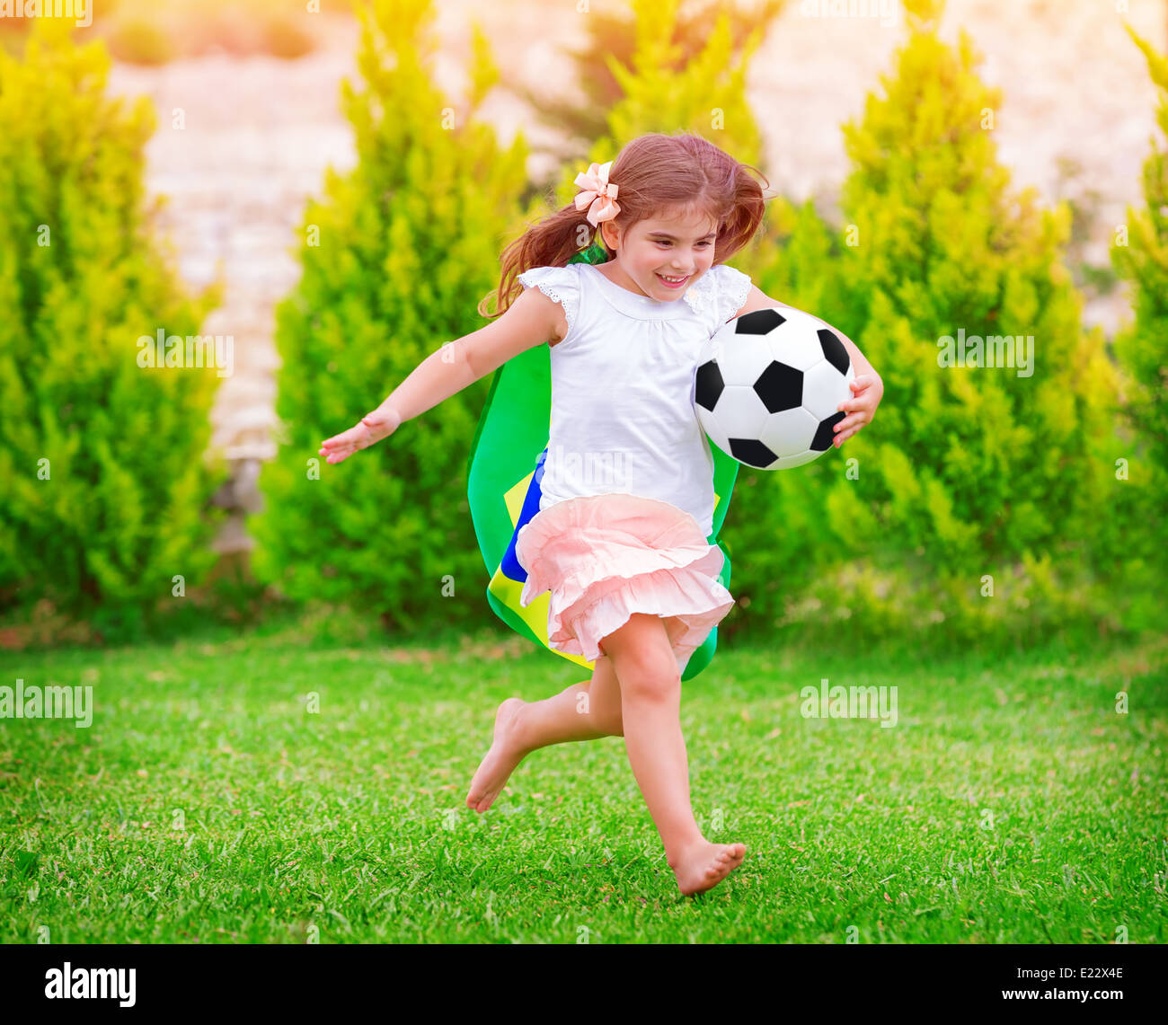 Little active football fan running on the green grass field with ball