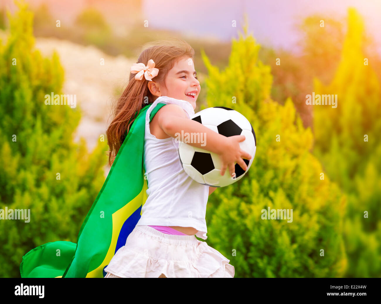Little active football fan running on the green grass field with ball