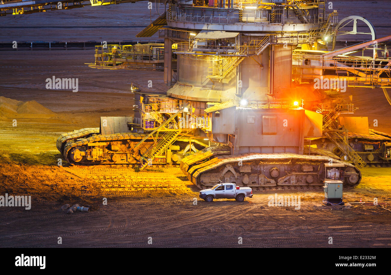 Caterpillats detail view of a giant Bucket Wheel Excavator next to a pickup truck at night Stock Photo