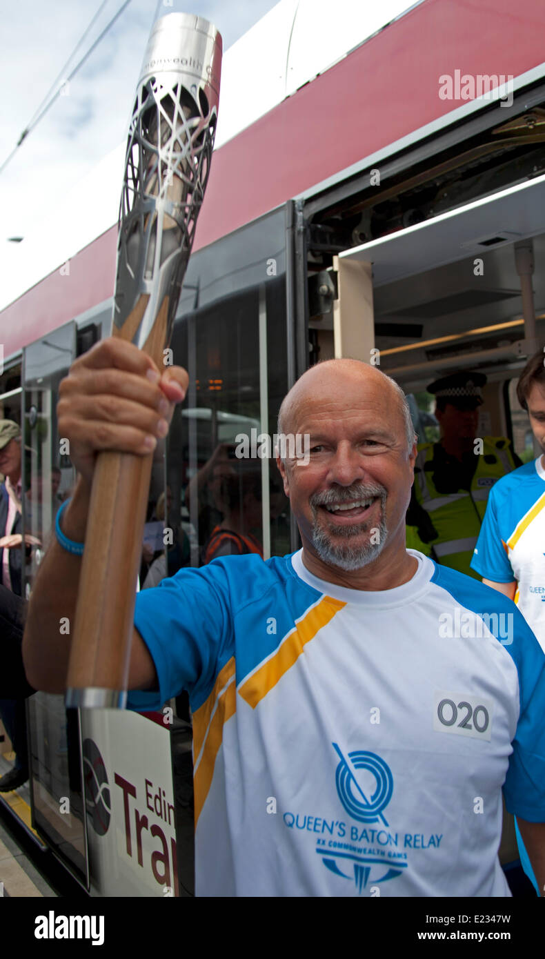 Edinburgh, Scotland, UK. 14th June 2014.  Queen's Baton Relay arrives in Edinburgh by Tram and Michael Laing spreads Commonwealth Games fever as he shows the baton to those lining the streets before it is passed on and weaves its way through the capital city's streets. Gavin Hastings former Scotland Rugby captain looks to the heavens in the Royal Mile. Credit:  Arch White/Alamy Live News Stock Photo