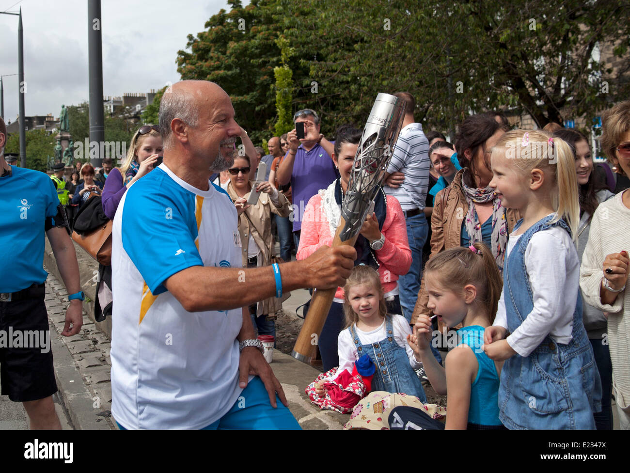 Edinburgh, Scotland, UK. 14th June 2014.  Queen's Baton Relay arrives in Edinburgh by Tram and Michael Laing spreads Commonwealth Games fever as he shows the baton to those lining the streets before it is passed on and weaves its way through the capital city's streets. Gavin Hastings former Scotland Rugby captain looks to the heavens in the Royal Mile. Credit:  Arch White/Alamy Live News Stock Photo