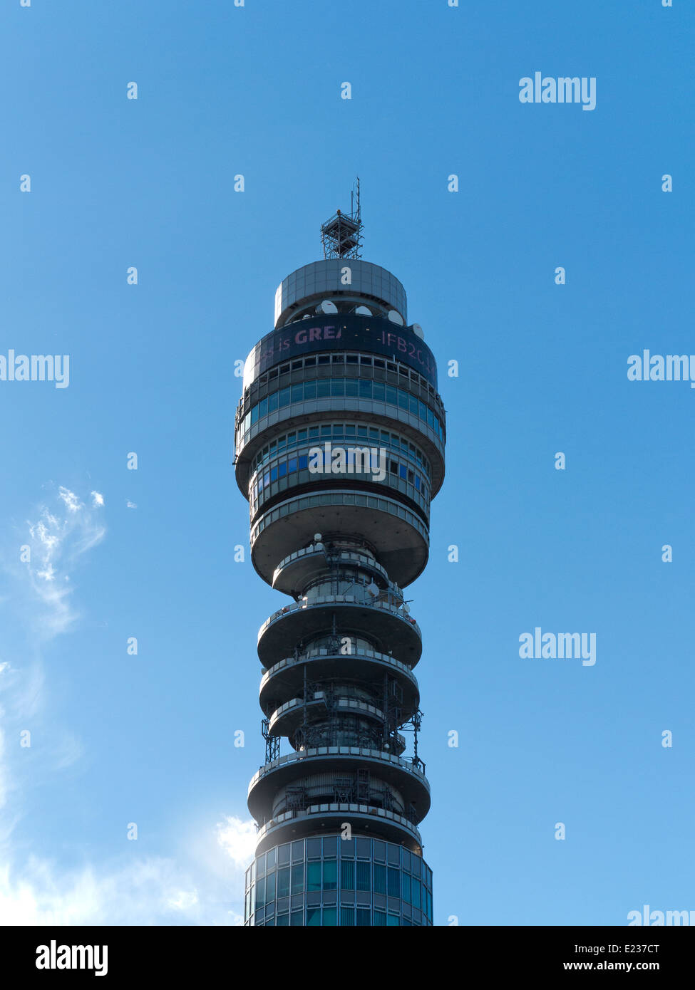 The top section of Telecom Tower against a blue sky with white clouds Stock Photo