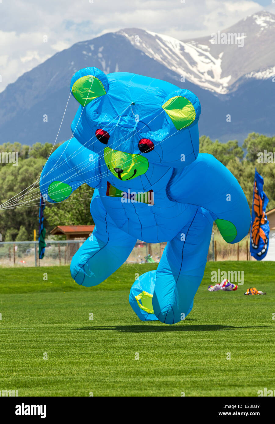 Large blue bear shaped kit flying above park fields Stock Photo