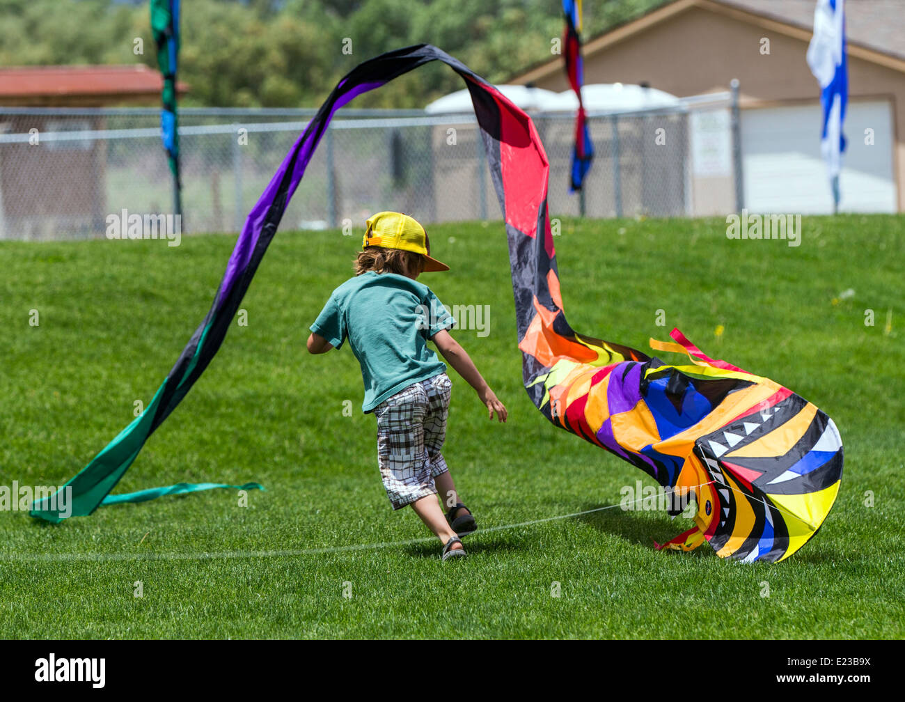 Young boy launching a kite on a grassy field Stock Photo