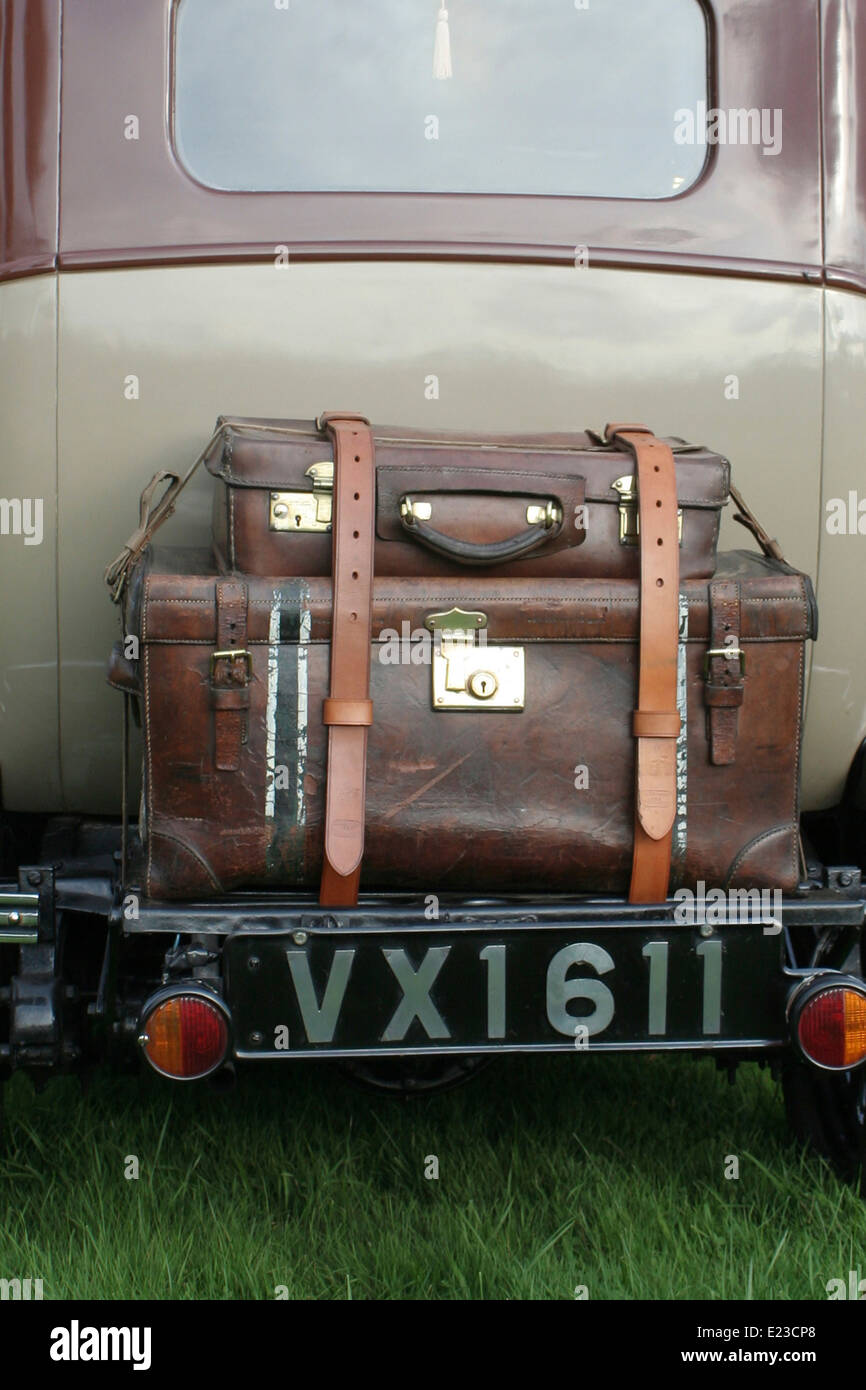 the back of a vintage car showing two well worn leather cases strapped to the back. Stock Photo