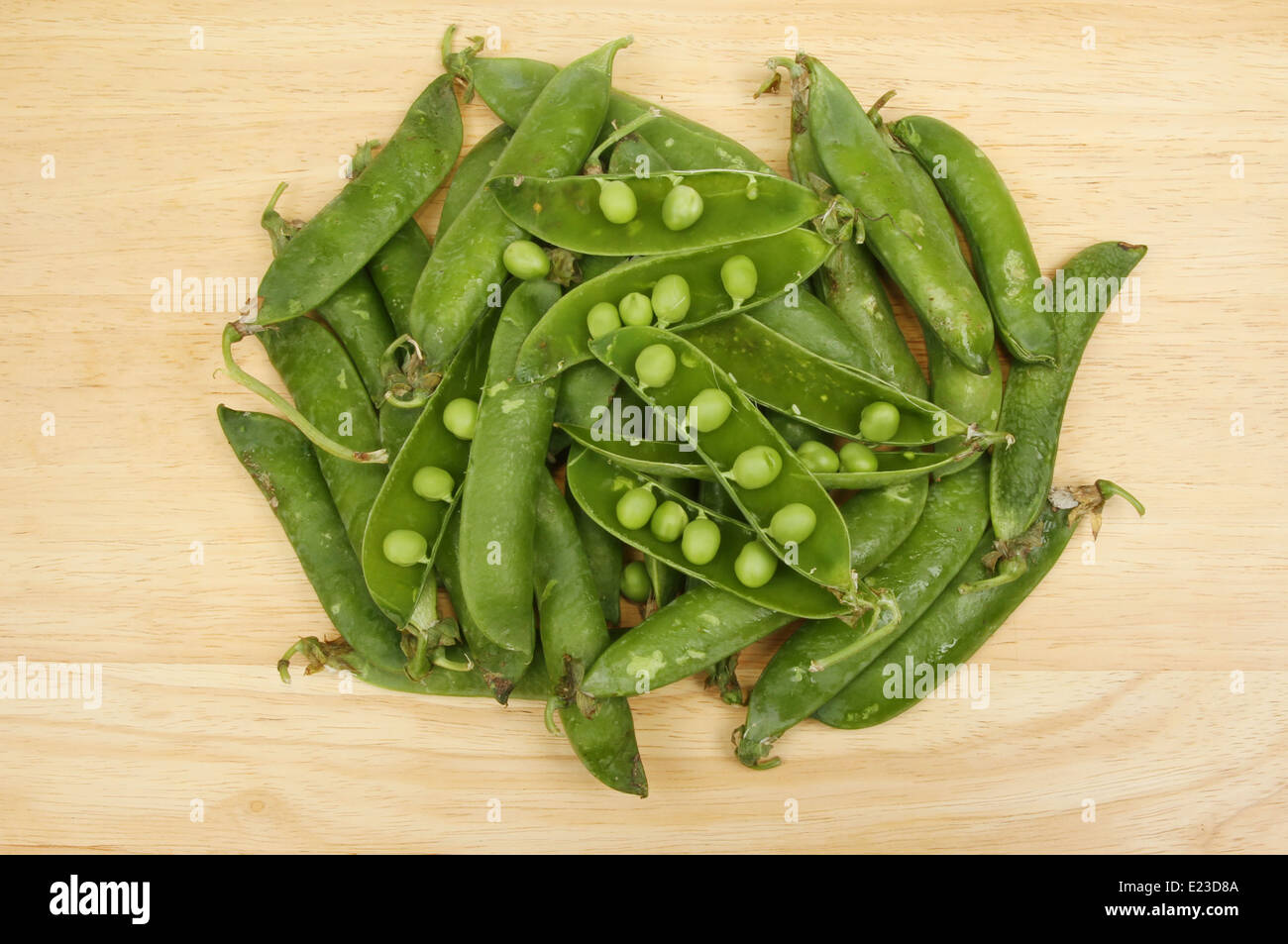 Fresh whole and split pea pods on a wooden board Stock Photo