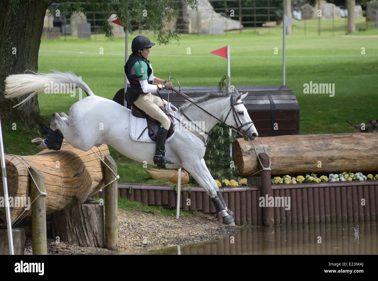 Louise Scammell riding Silver  Sovereign over the log fence into the water Stock Photo