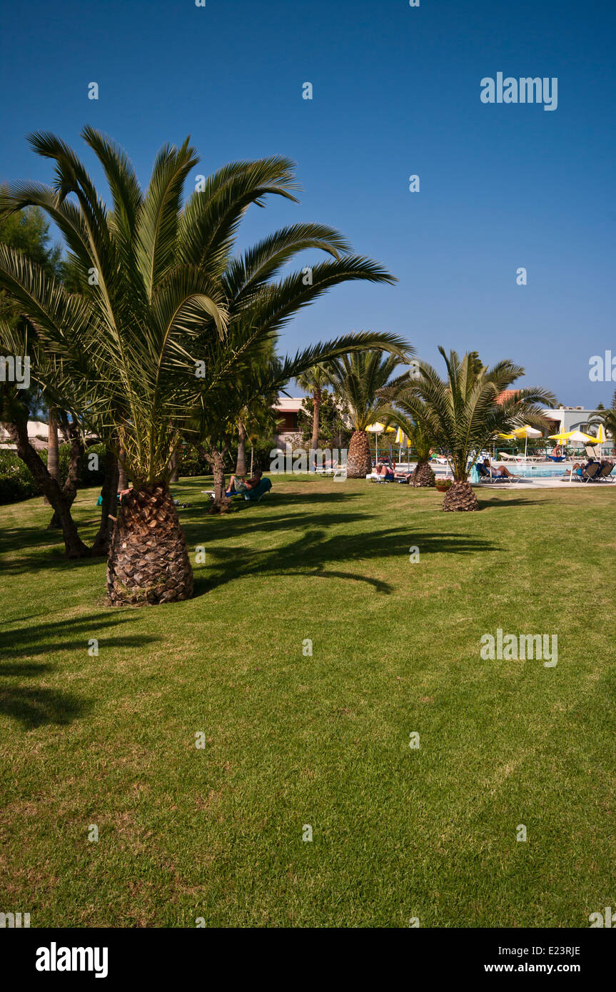 Holidaymakers Relaxing Around The Swimming Pool In Hotel Gardens with Blue Skies Stock Photo