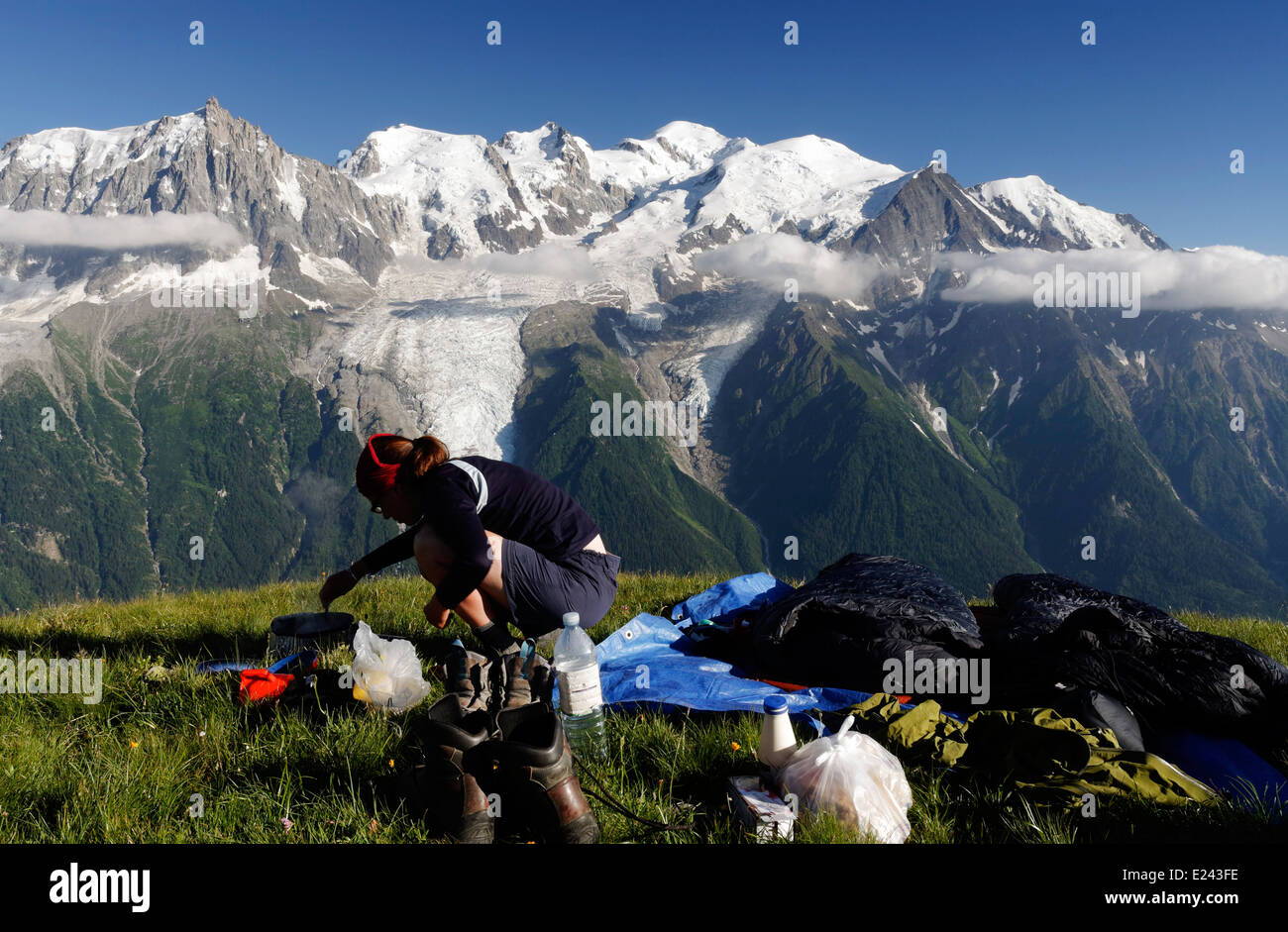 A lady camper preparing food wild camping on le Brevent  in the French Alps with the Mont Blanc massif beyond Stock Photo