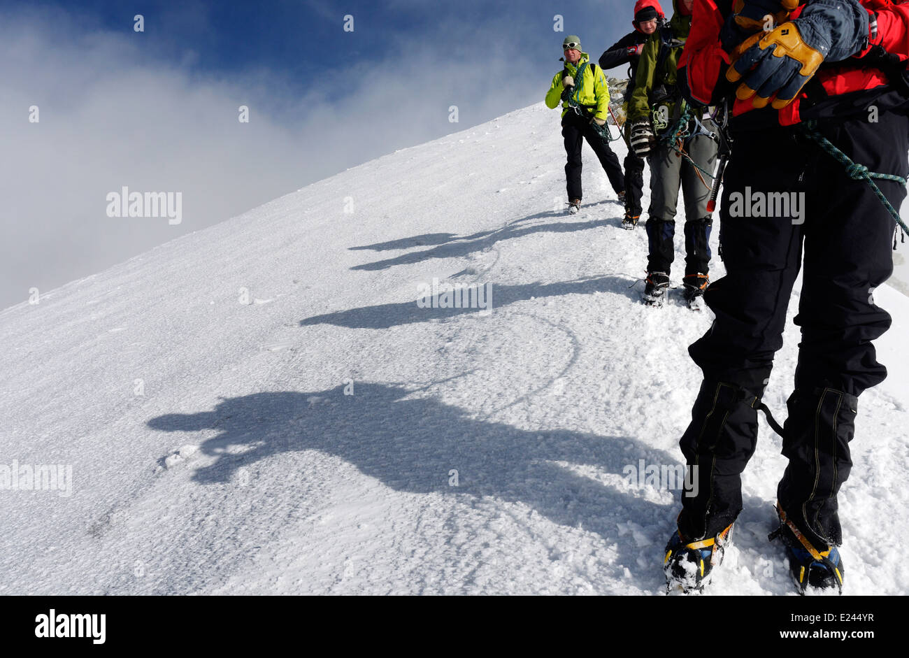 A rope of four climbers and their shadows Stock Photo