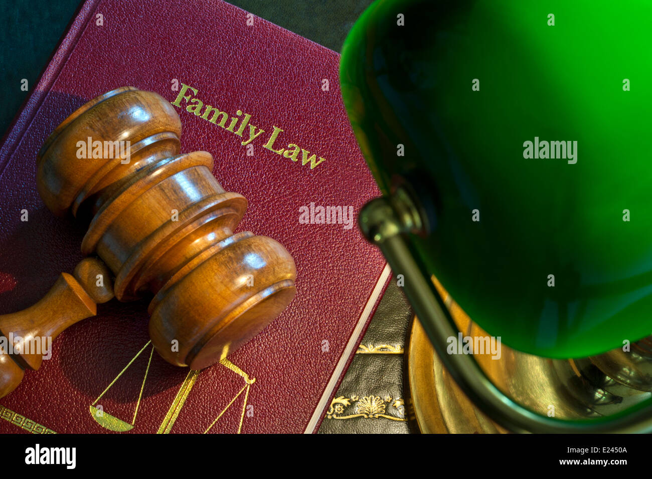 Judges wooden gavel on 'Family Law' book with scales of justice emblem illuminated by traditional desk lamp Stock Photo