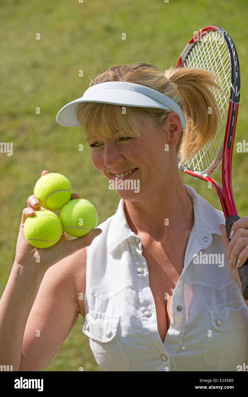 Female tennis player holding racquet and three balls in her hand Stock Photo