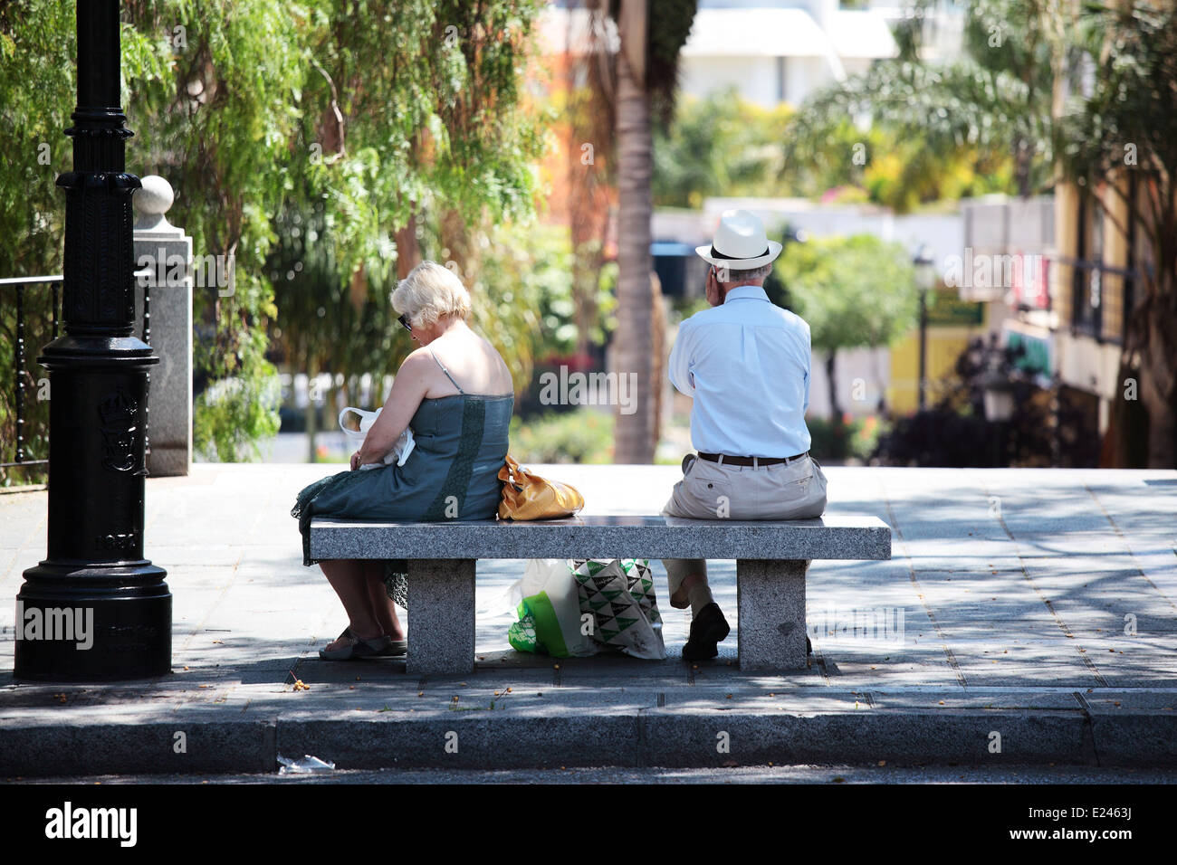Old couple on bench ignoring each other Stock Photo
