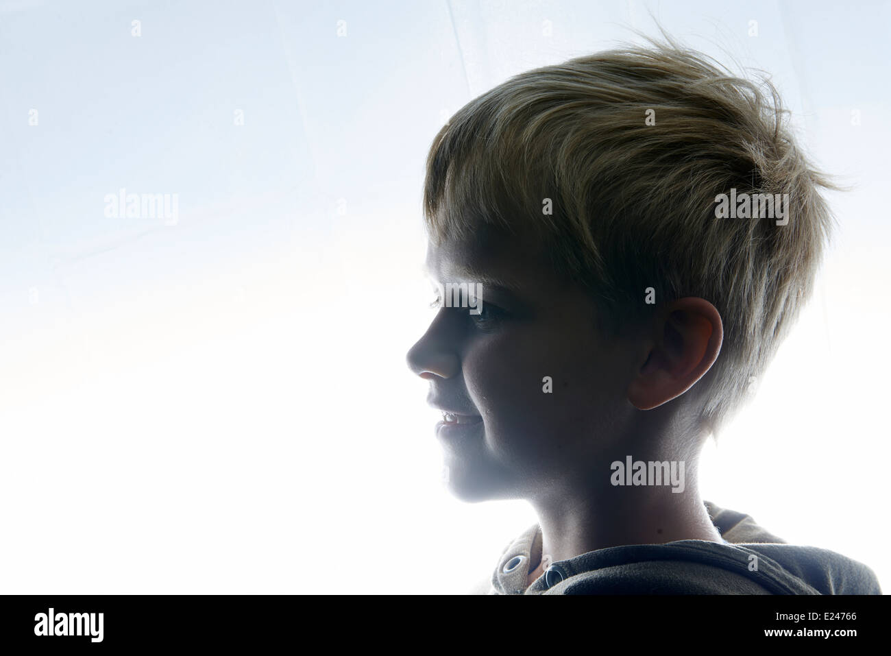 Portrait of a Young child Boy Silhouetted Against a white lights background Stock Photo