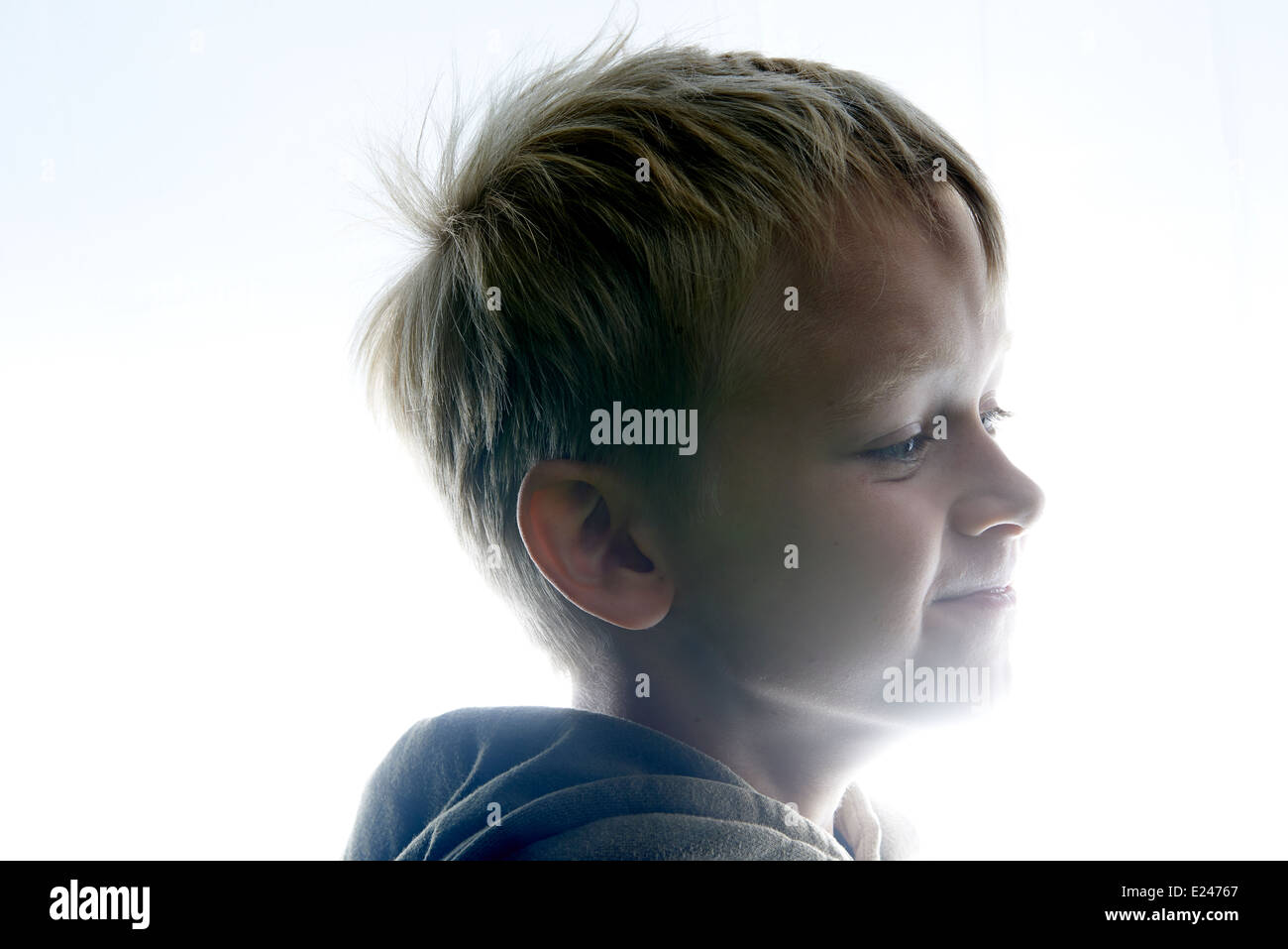 Portrait of a Young child Boy Silhouetted Against a white lights background Stock Photo
