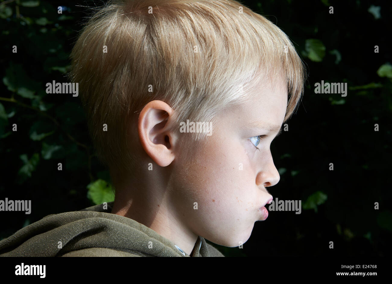 Headshot, side view Portrait Angry Child  isolated dark background. Negative Human face Expressions, Emotions, Conflict, Grimace Stock Photo