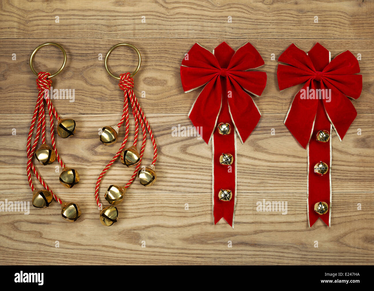 Overhead view of Christmas red bows and rope with golden bells positioned on rustic wooden boards. Stock Photo