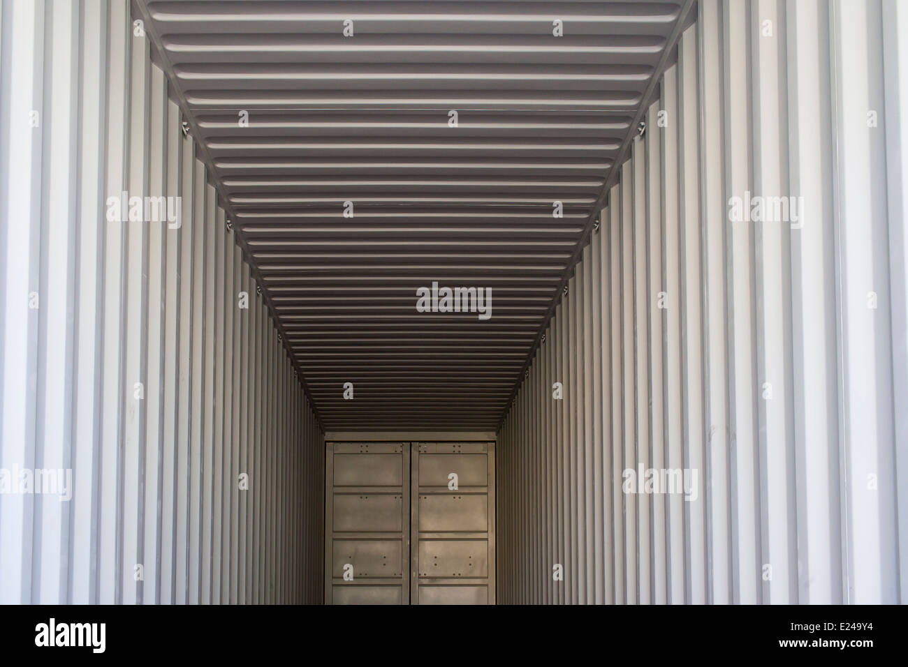 A symmetrical image of the interior of a standard cargo shipping container. The floor is covered with protective paper. Stock Photo