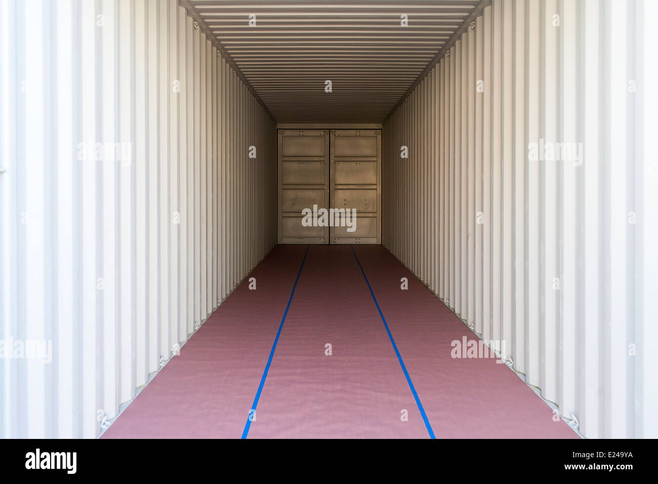 A symmetrical image of the interior of a standard cargo shipping container. The floor is covered with protective paper. Stock Photo