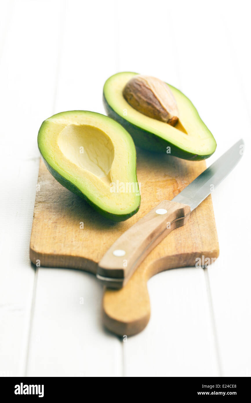 halved avocados on white wooden table Stock Photo - Alamy