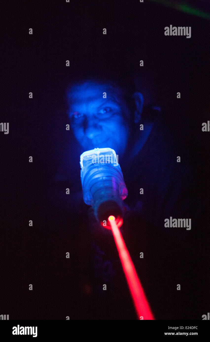 A man playing a laser / lazer gun war game in a special darkened arena  under UV lighting - his face glowing Stock Photo - Alamy