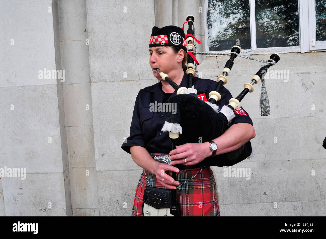 A female Scottish piper plays bagpipes in London Stock Photo