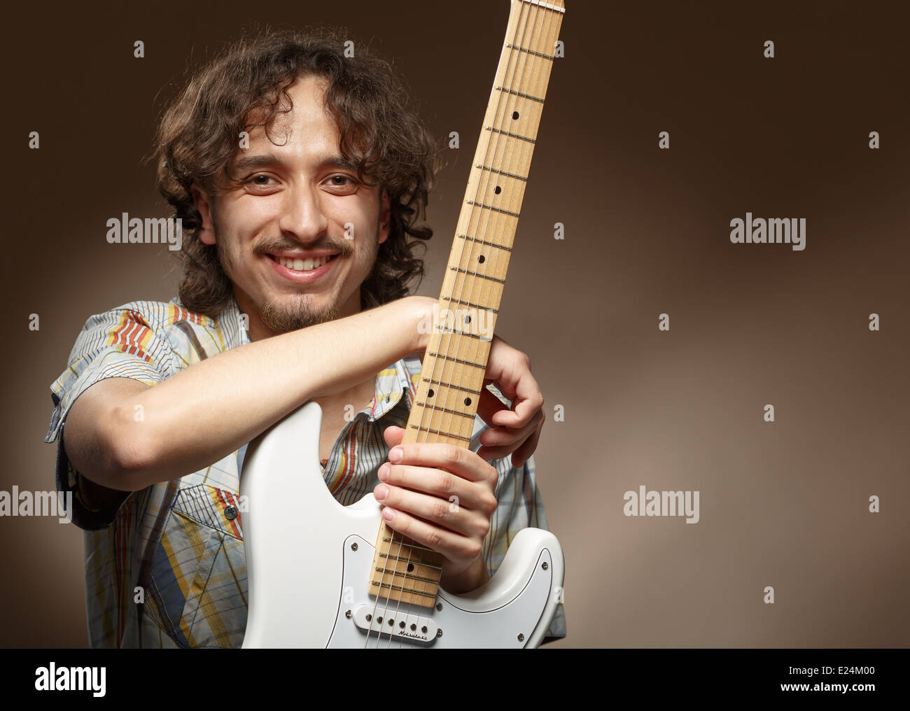 Young musician posing in studio with a guitar. Hispanic. Free space on
