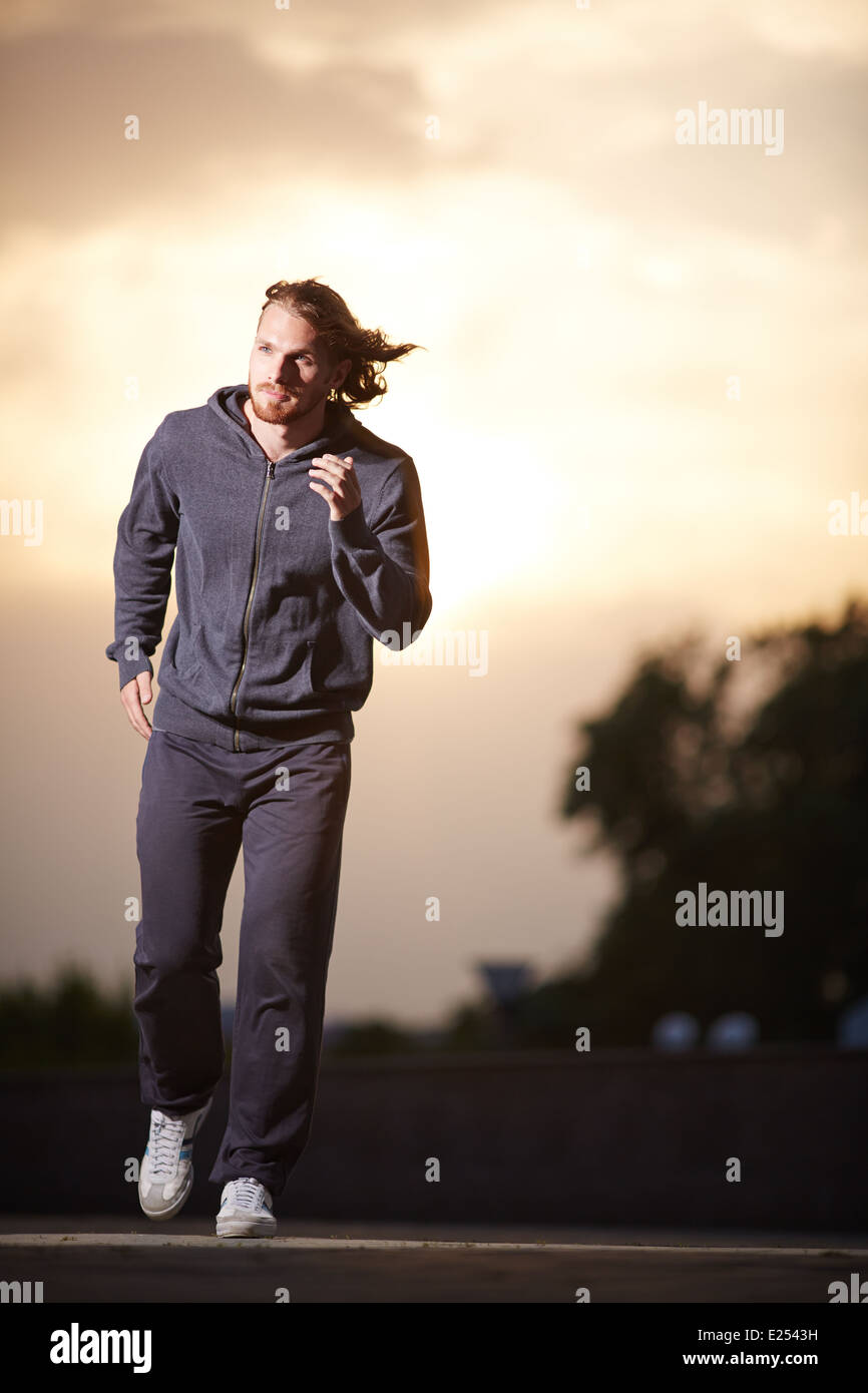 Portrait of young sportsman running in the evening Stock Photo
