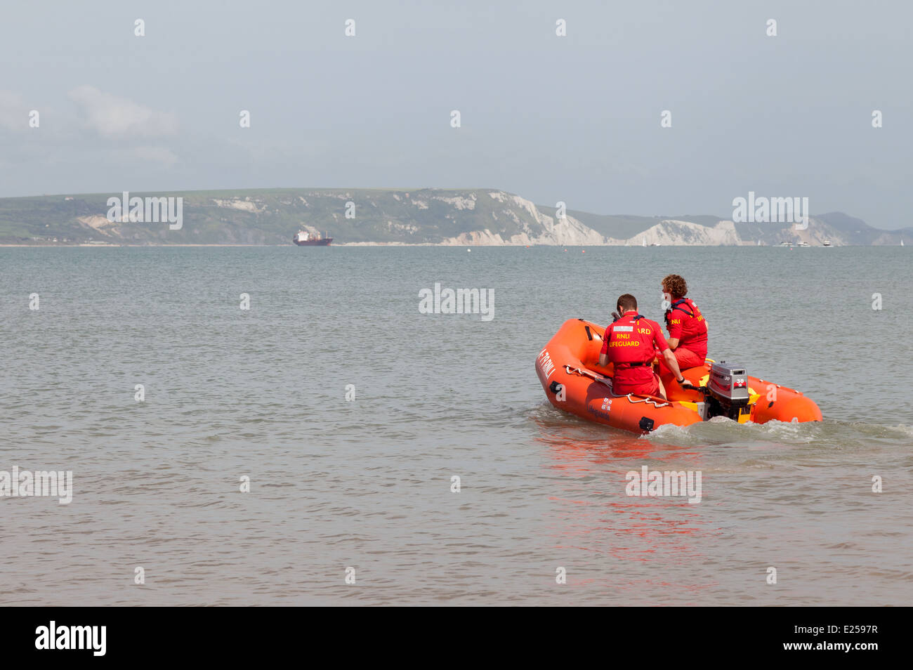 RNLI Lifeguard going out by rescue boat, Weymouth Beach, Dorset England UK Stock Photo