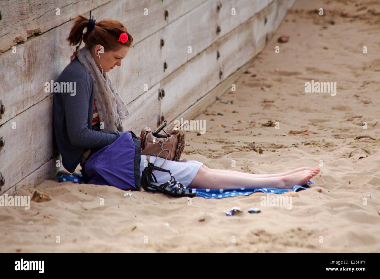 Young woman sitting on beach listening to music at Bournemouth beach in June. Credit:  Carolyn Jenkins/Alamy Live News Stock Photo