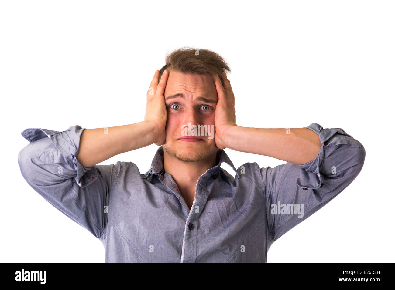 Desperate, upset young man with hands on his face and looking at camera Stock Photo