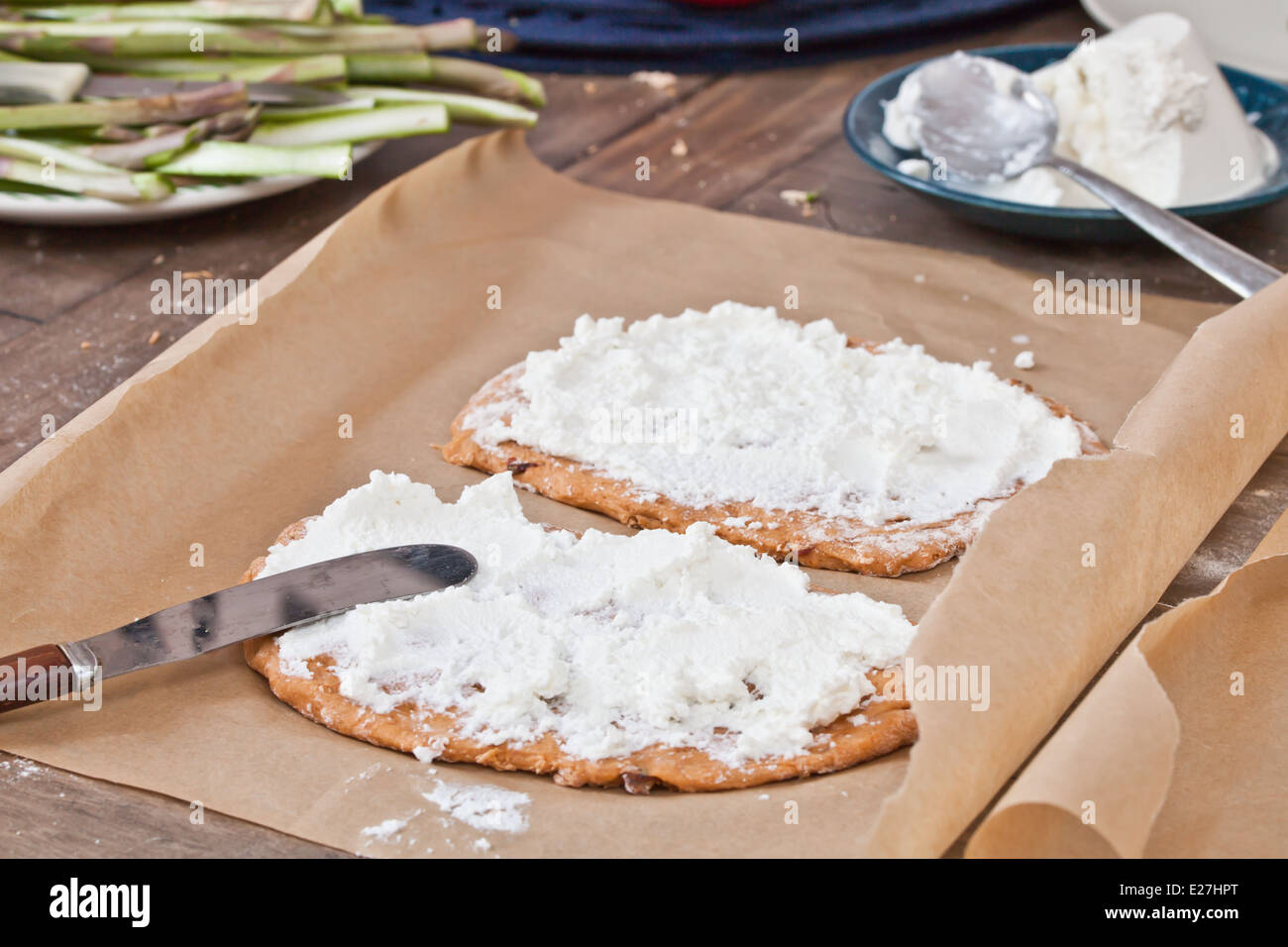 Pizza bases with ricotta cheese and asparagus ready for baking Stock