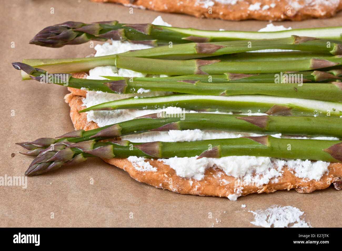 Pizza bases with ricotta cheese and asparagus ready for baking Stock
