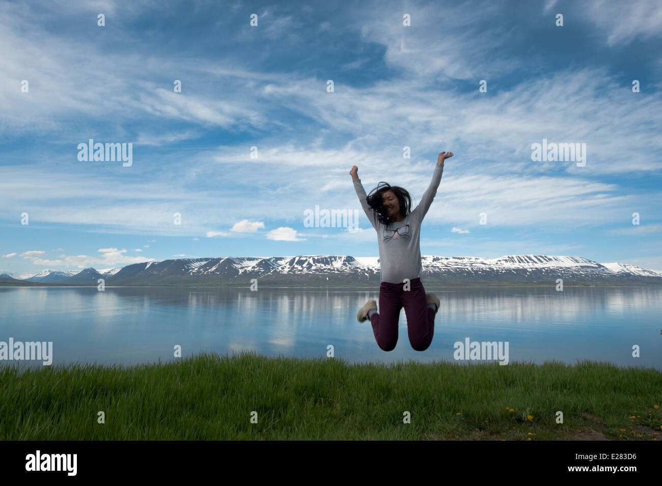 young girl jump with a blue sky and snow mountain as background Stock Photo
