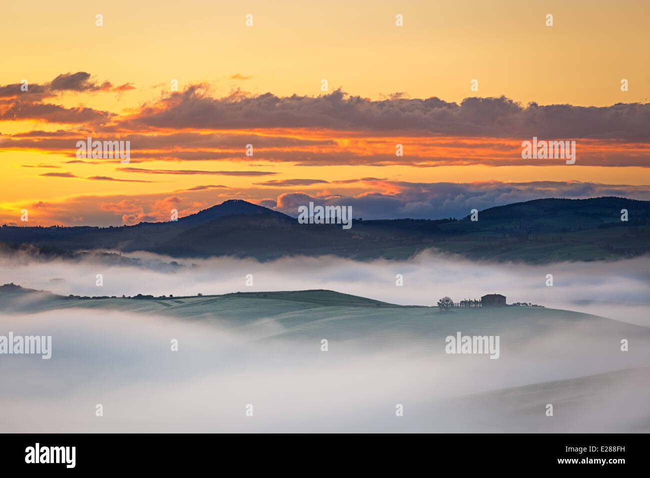 Farmhouse near in Val d'Orcia at foggy dawn, Tuscany, Italy Stock Photo
