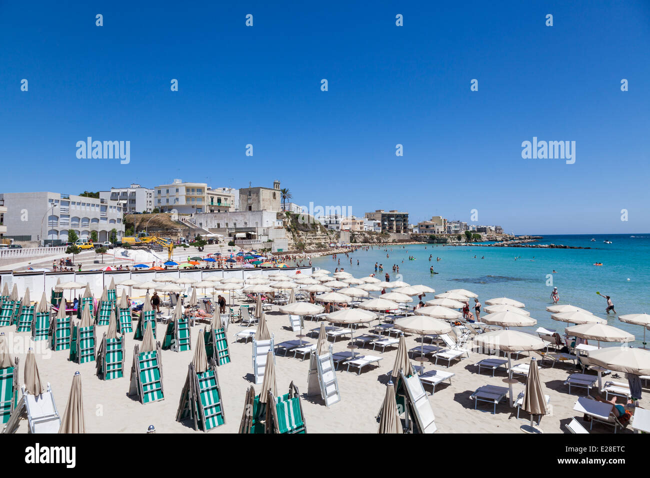 Beach parasols and sunloungers on a sunny beach in Otranto, Puglia, Salento region of southern Italy Stock Photo