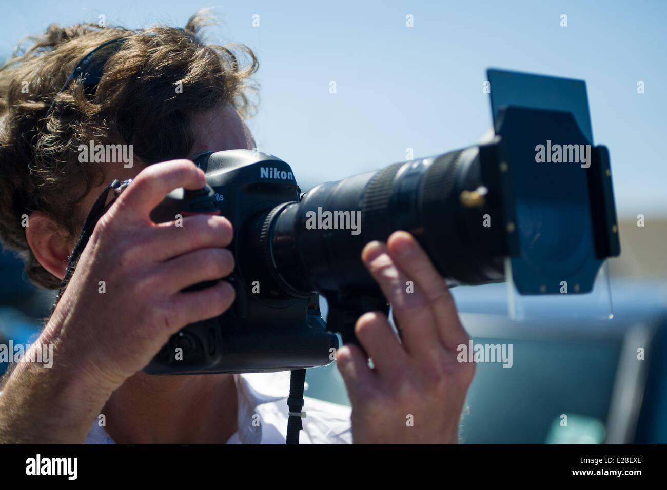 A photographer photographs using a graduated neutral density filter. Stock Photo