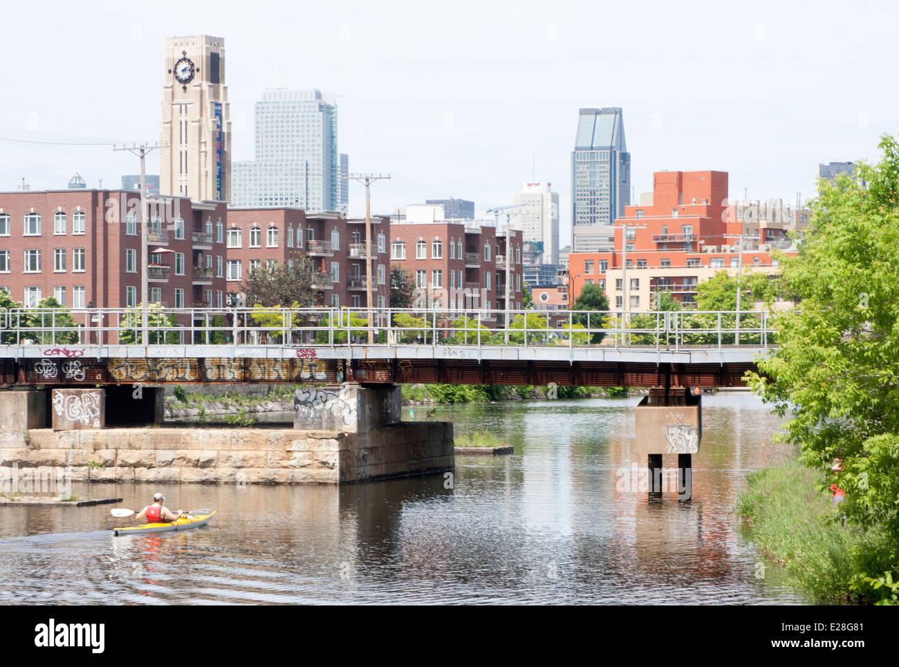 A man kayaks along the Lachine Canal in Montreal, with downtown and Atwater Market in the background Stock Photo