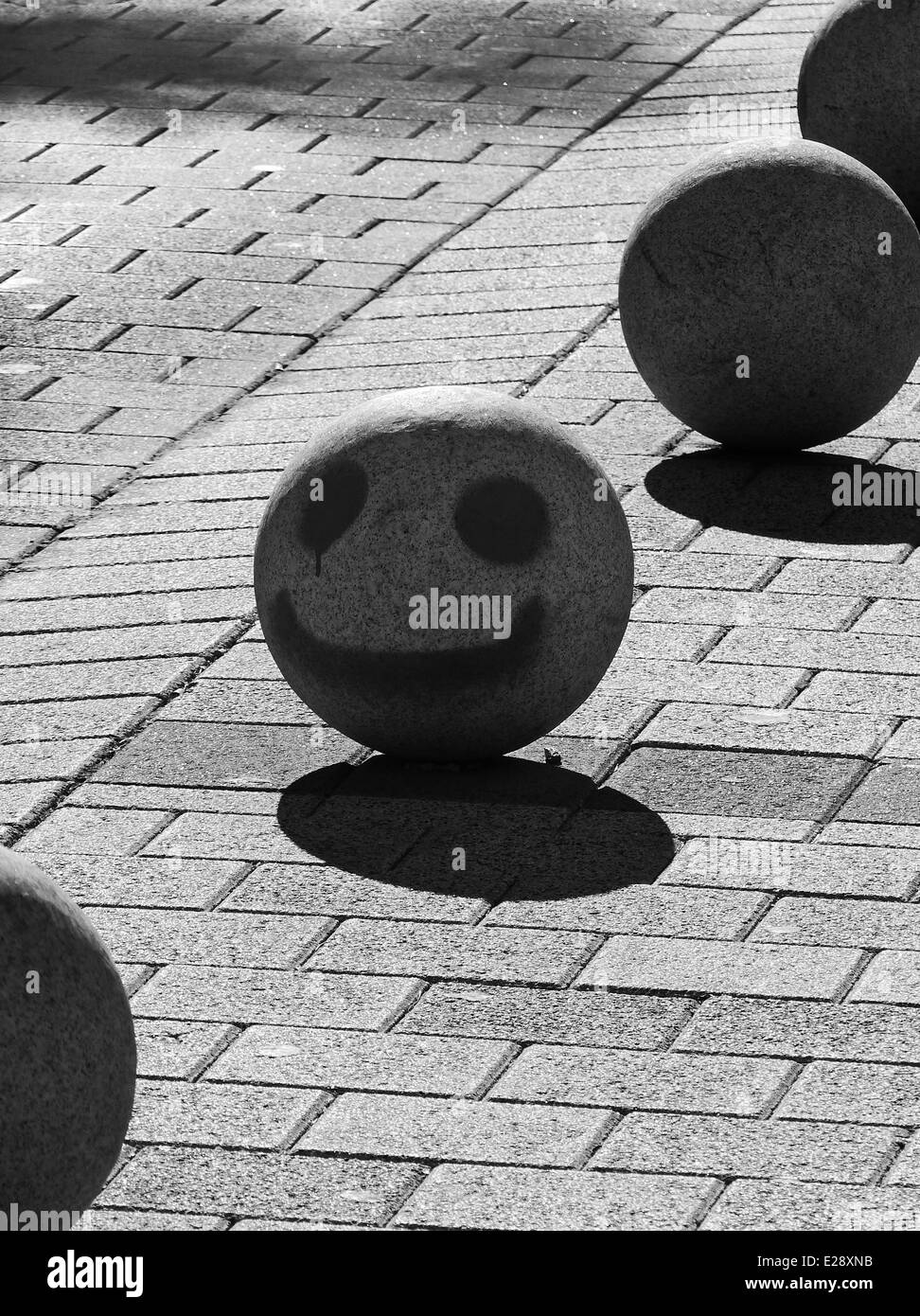A concrete ball with smiley face graffiti Stock Photo
