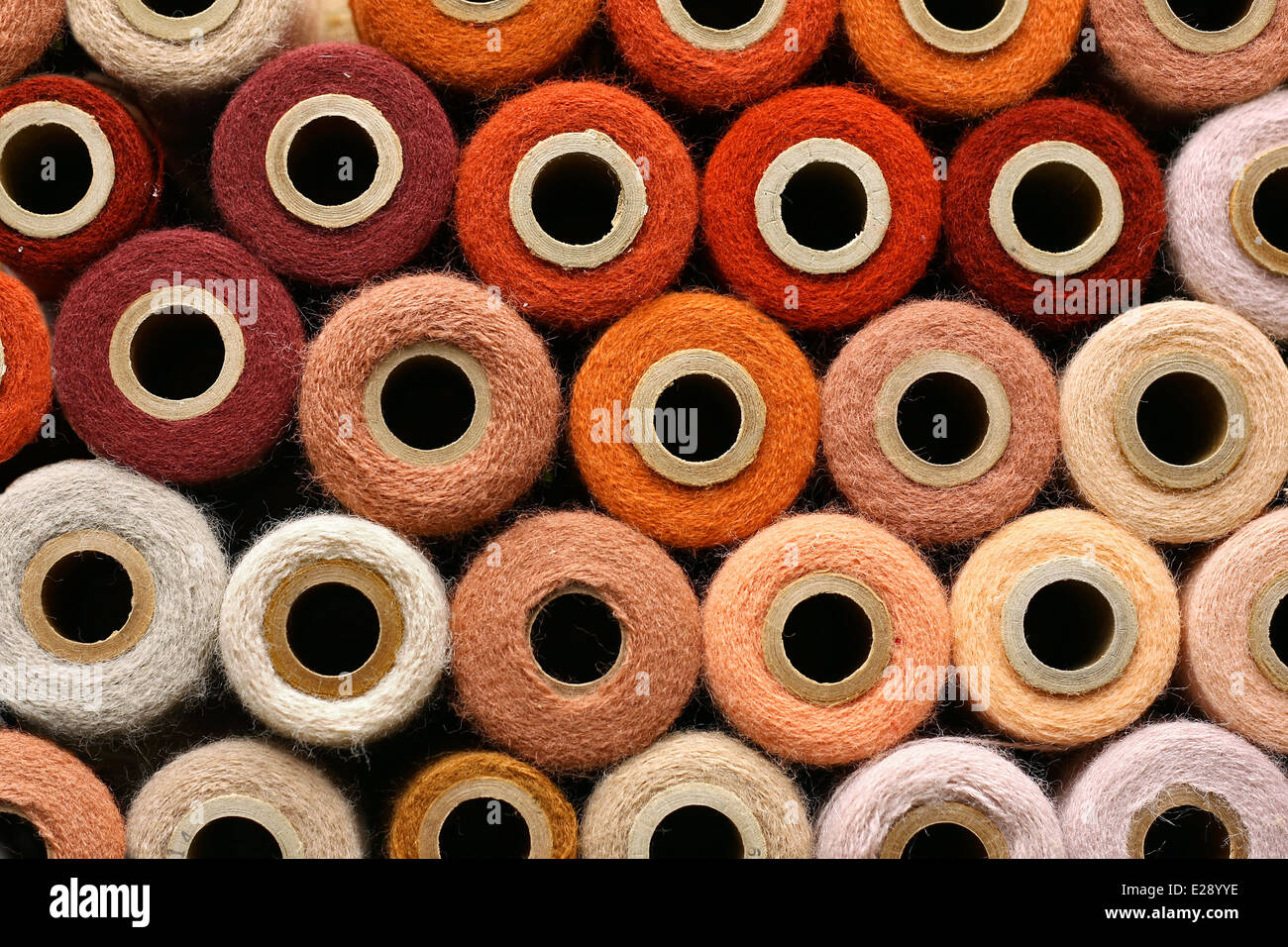 a large collection of Orange and other colorful vintage craft yarn spools gathered as a background. Stock Photo