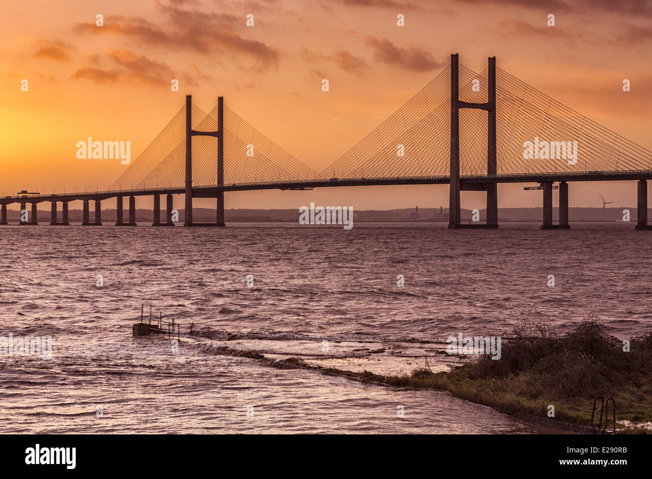 View of jetty, harbour wall and road bridge during very high tide and stormy conditions at sunrise, Sudbrook Jetty, Second Severn Crossing, River Severn, Severn Estuary, Monmouthshire, Wales, January Stock Photo