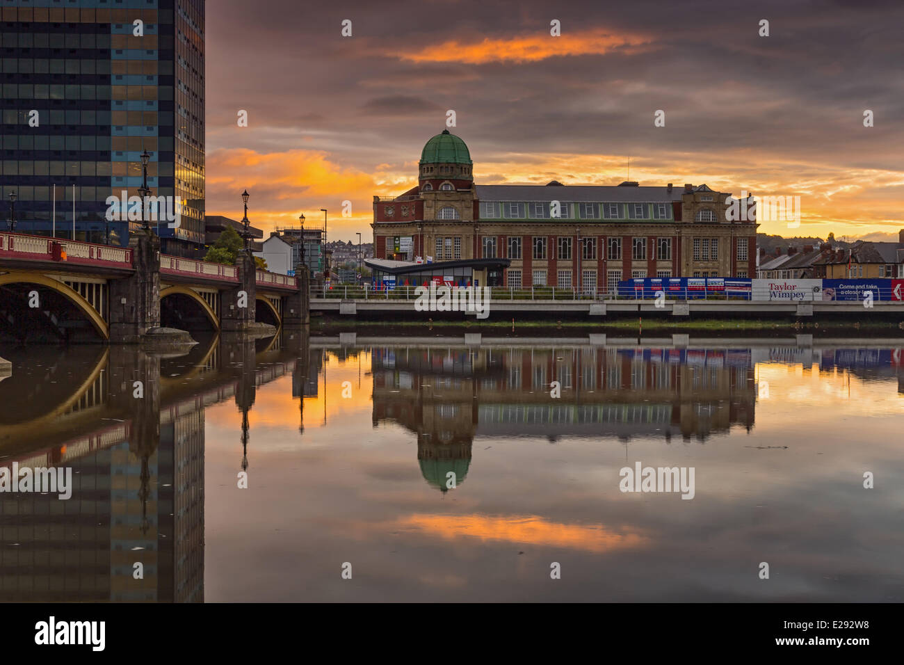 Redeveloped apartment building with copper dome, reflected in river at sunrise, Newport Technical Institute, River Usk, Newport, South Wales, October Stock Photo