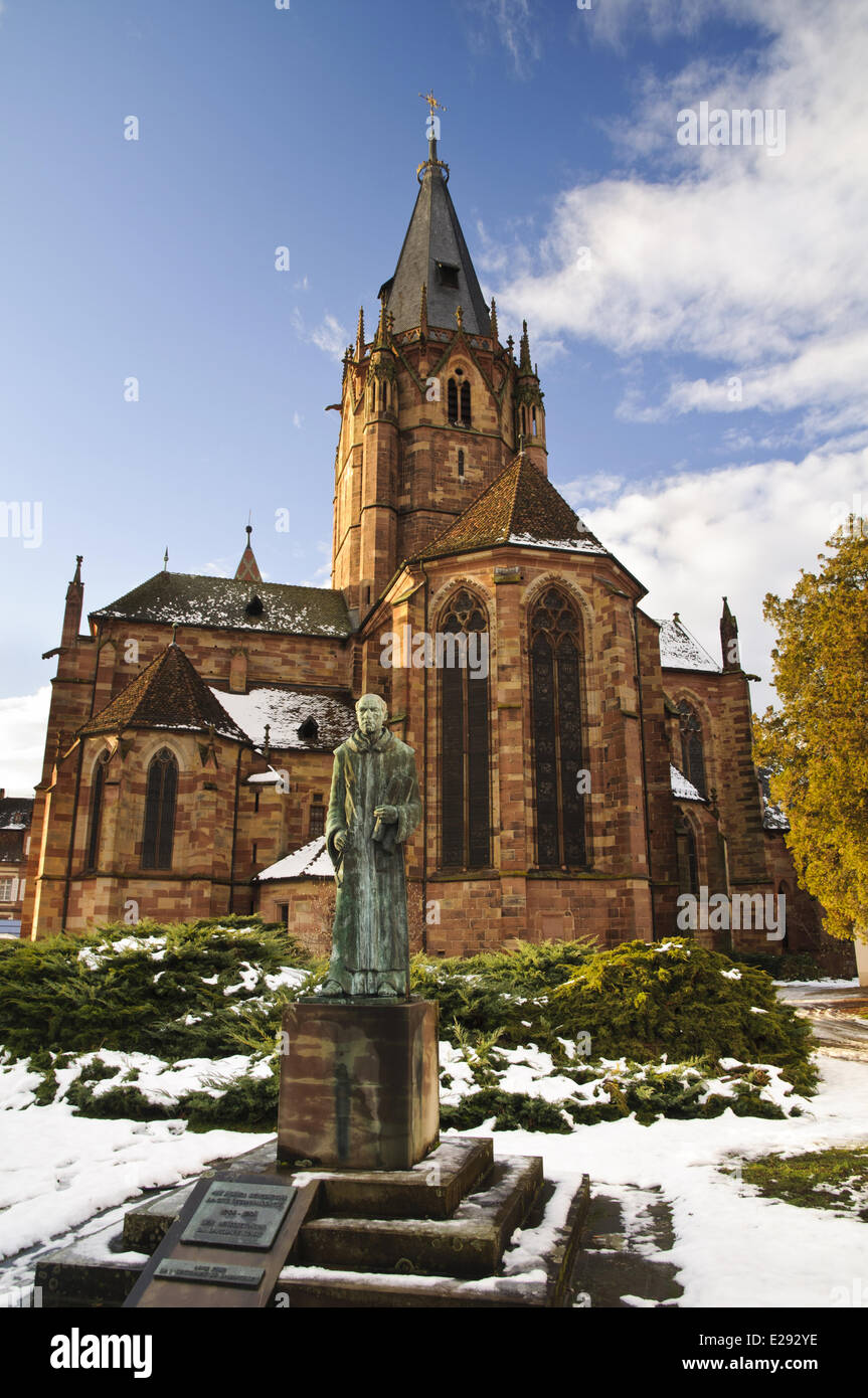 Statue of Benedictine monk and Roman Catholic church in snow, St. Peter and St. Paul's Church, Wissembourg, Bas-Rhin, Alsace, France, December Stock Photo