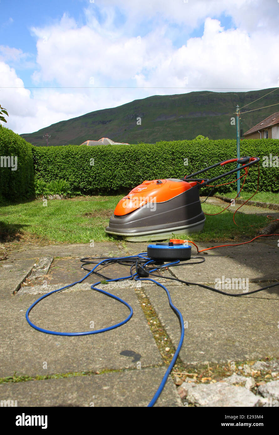 Mowing grass in garden with Flymo hover lawn mower Stock Photo