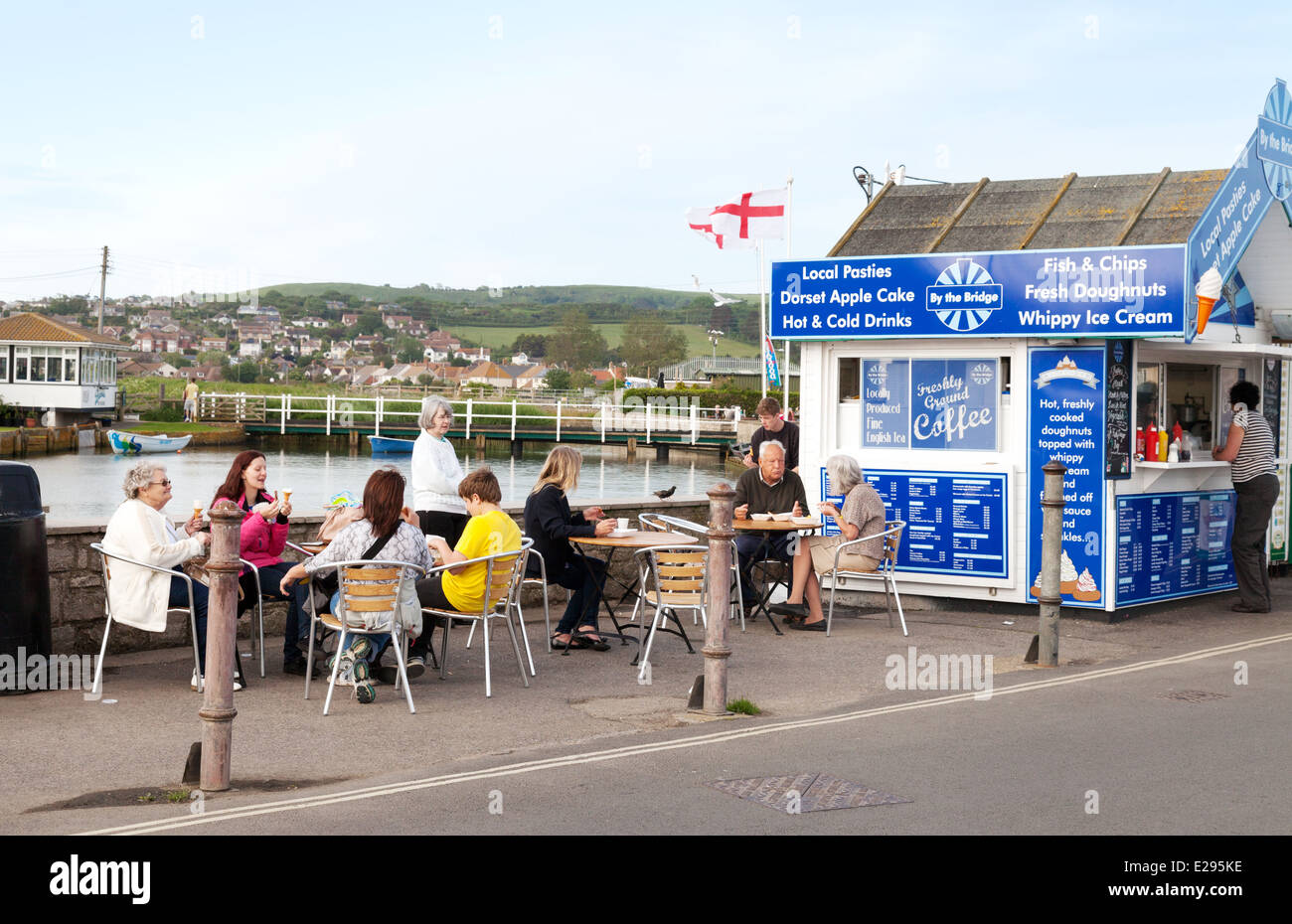 People eating fish and chips at a fish and chip shop, West Bay, Bridport Harbour, Dorset coast, England UK Stock Photo