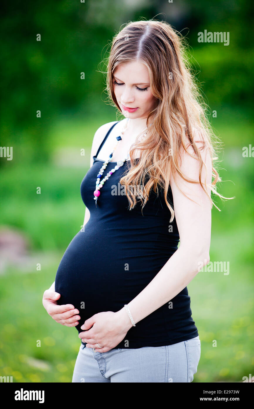 Young pregnant woman holding hands on her belly Stock Photo - Alamy