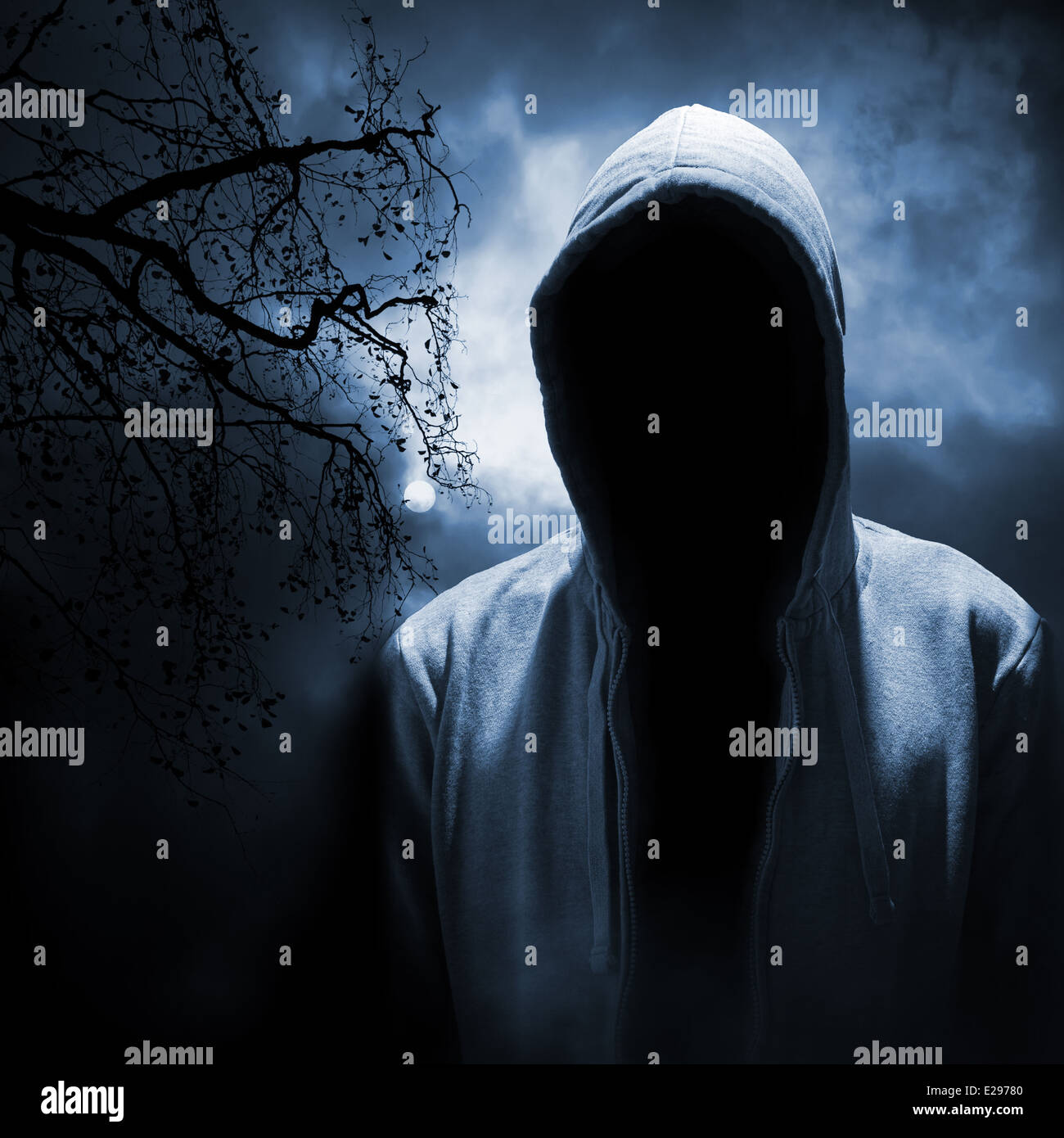 Dangerous man hiding under the hood in the dark night forest Stock Photo