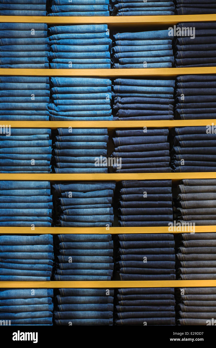 Neat stacks of folded jeans on the shop shelves Stock Photo