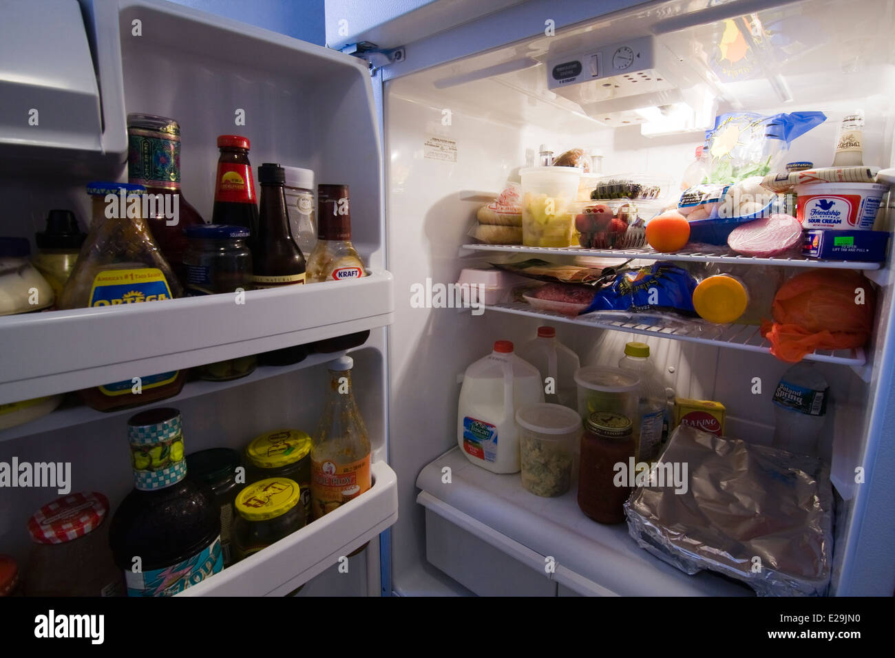 Door to a Refrigerator open with light on showing contents Stock Photo