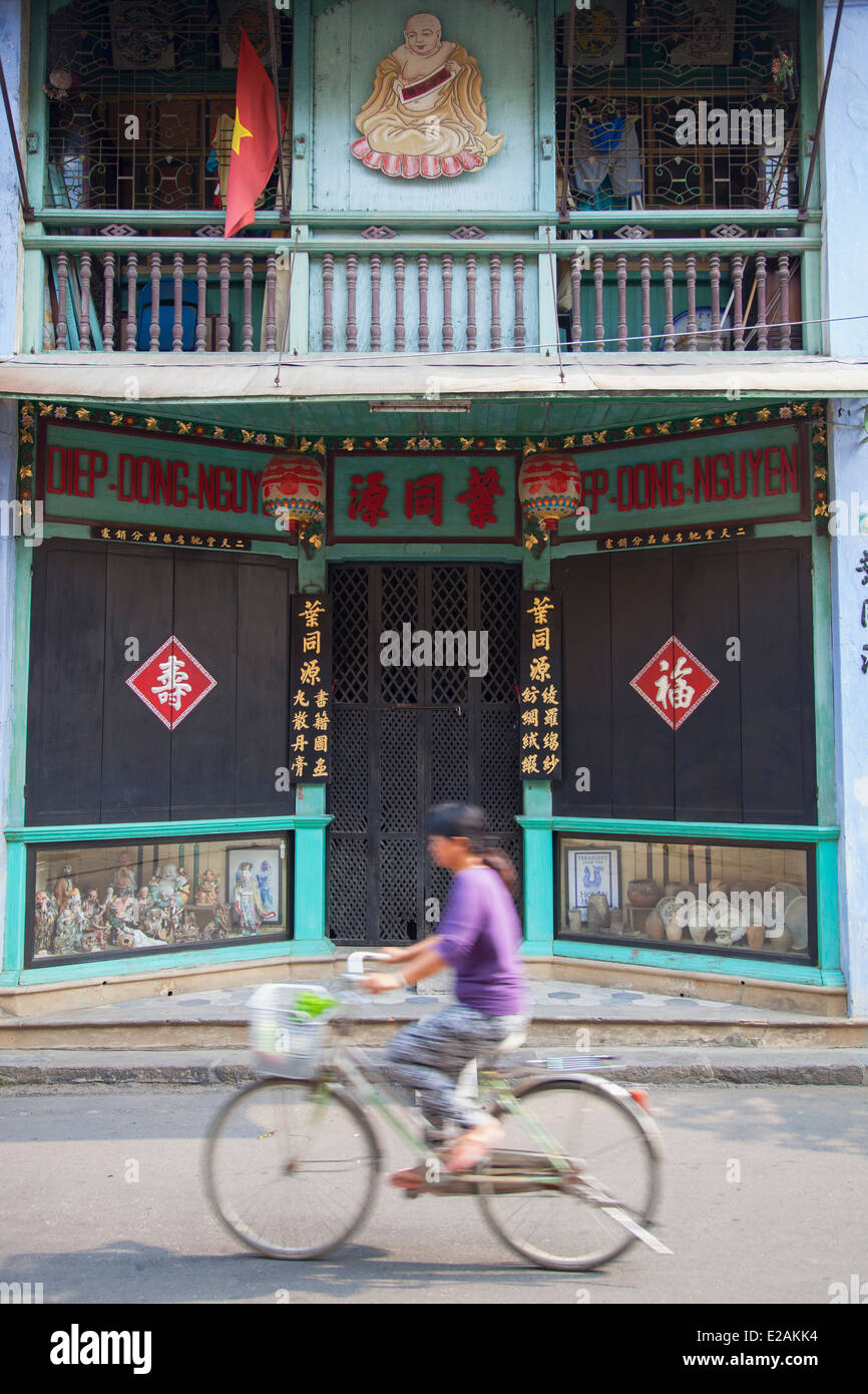 Woman riding bicycle past Chinese shop front, Hoi An (UNESCO World Heritage Site), Quang Ham, Vietnam Stock Photo